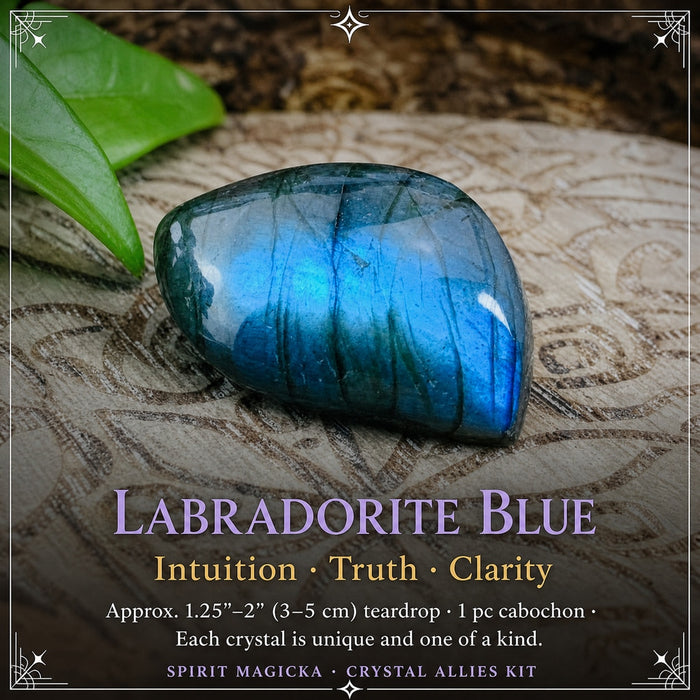 A polished blue labradorite teardrop cabochon with bright blue flash on a carved wood board