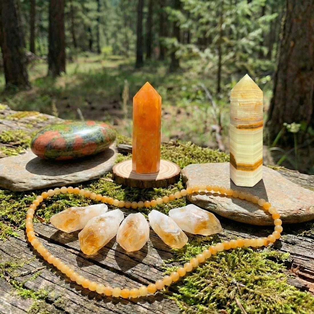 The full set on a mossy log: an unakite palmstone, an orange calcite point, a banded Afghanistan jade point, five citrine shards and a yellow aventurine bead necklace