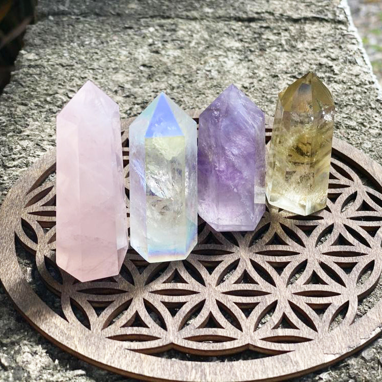 Rose quartz, Angel Aura quartz, amethyst and citrine points standing in a row on a wooden flower-of-life board