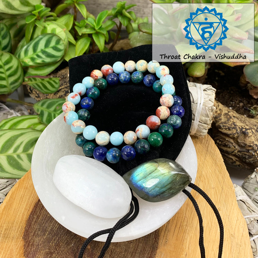 Azurite and azure variscite mala bracelets on a black velvet pouch with a white selenite ellipse and a blue-flashing labradorite cabochon