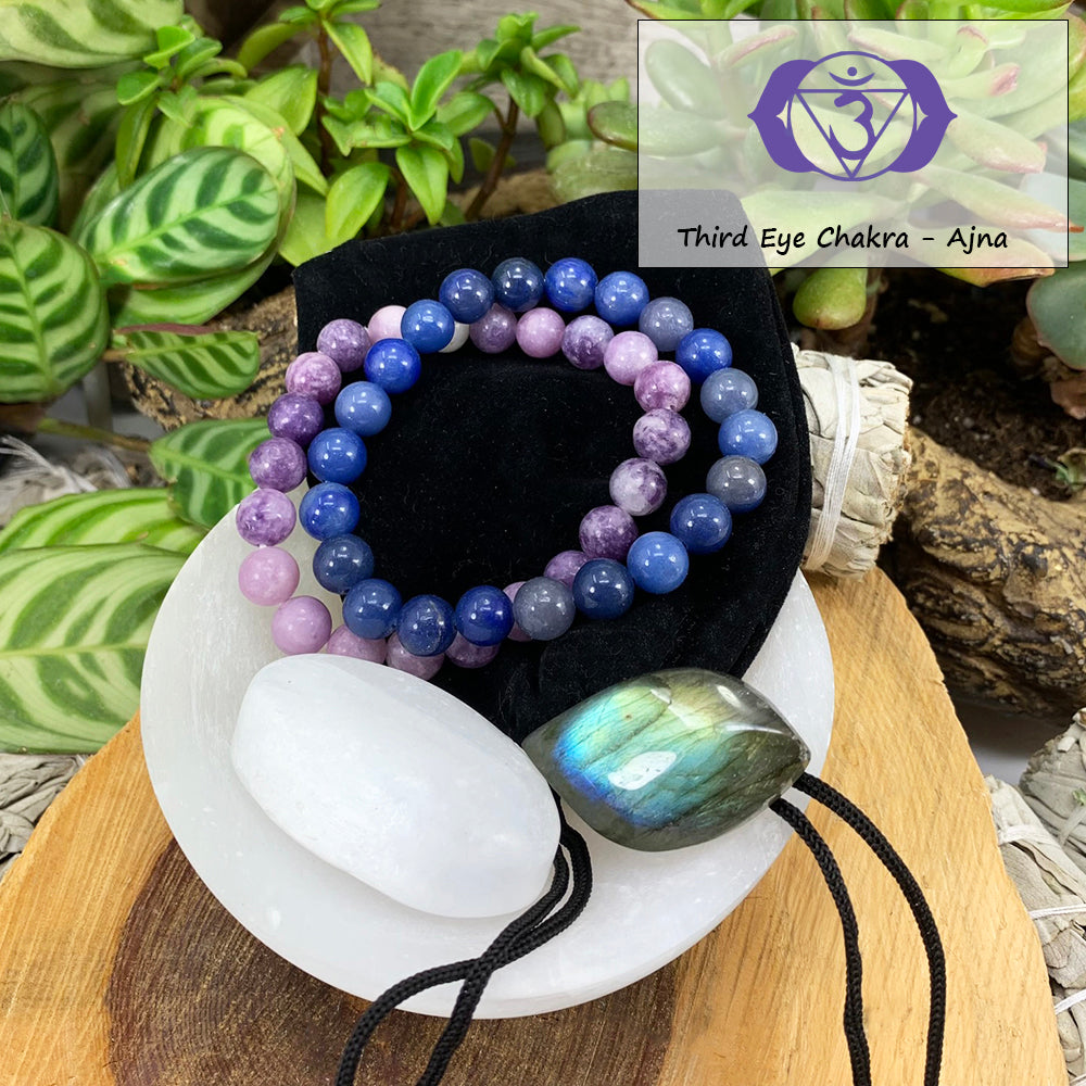 Lepidolite and blue aventurine mala bracelets on a black velvet pouch with a white selenite ellipse and a blue-flashing labradorite cabochon