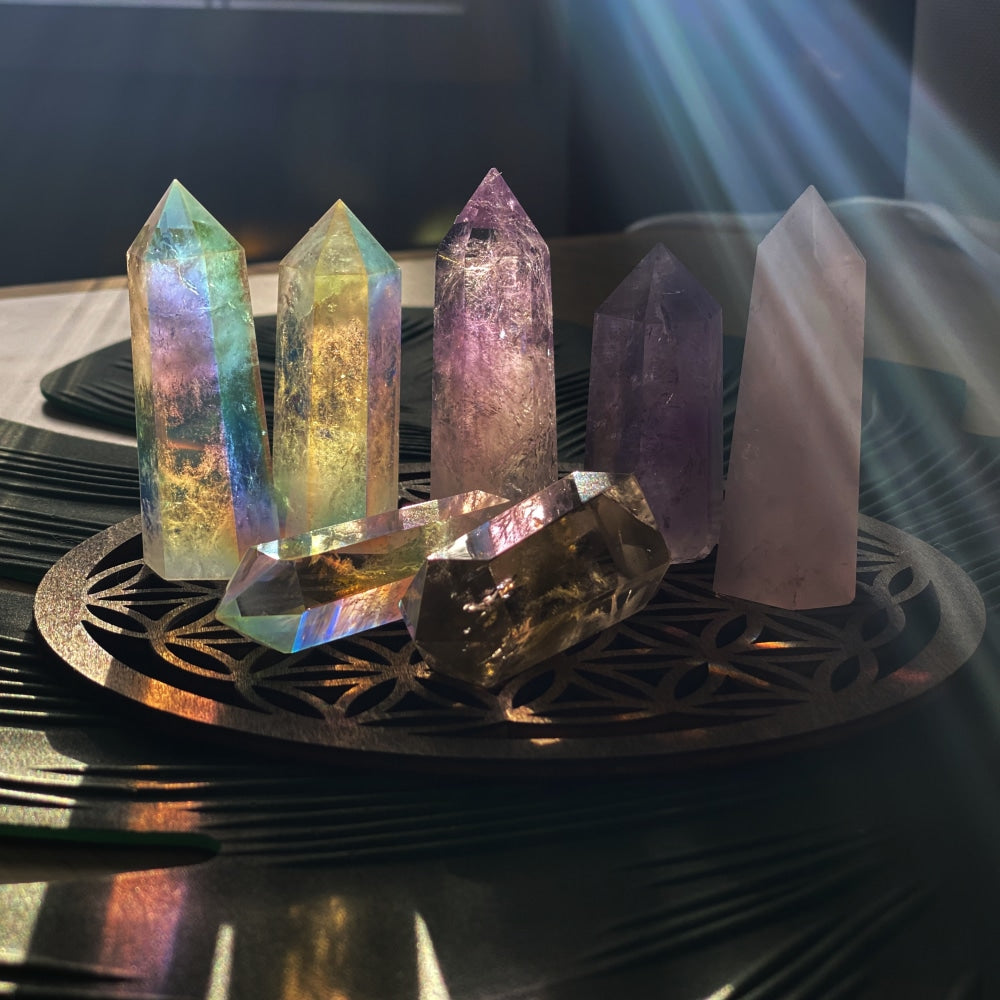 All seven points together on a carved tray in a beam of sunlight: three angel aura, two amethyst, one rose quartz and one smoky quartz