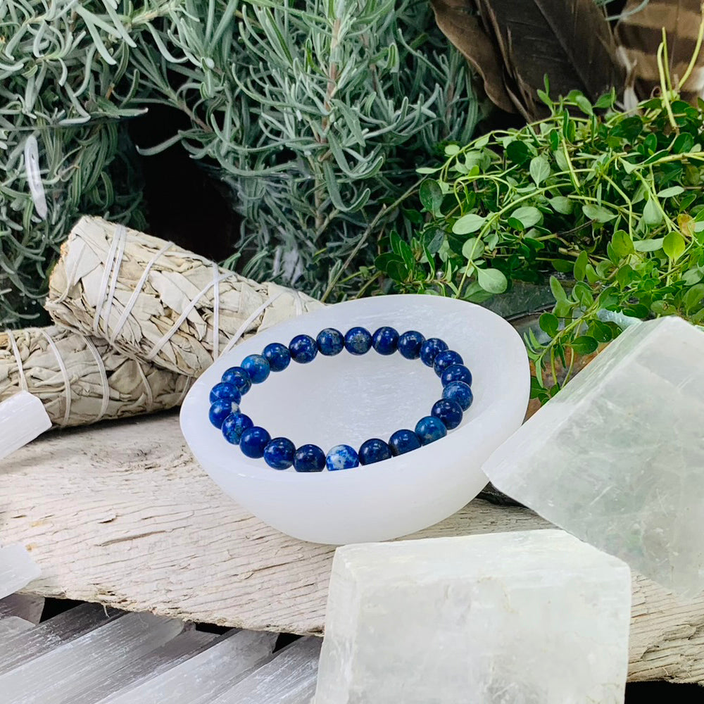 Lapis lazuli mala bracelet of round deep blue beads resting in a selenite bowl