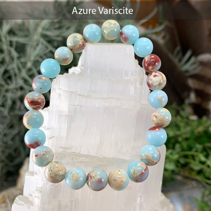 Sky-blue azure variscite bead bracelet with cream and rust-red veining on a selenite tower