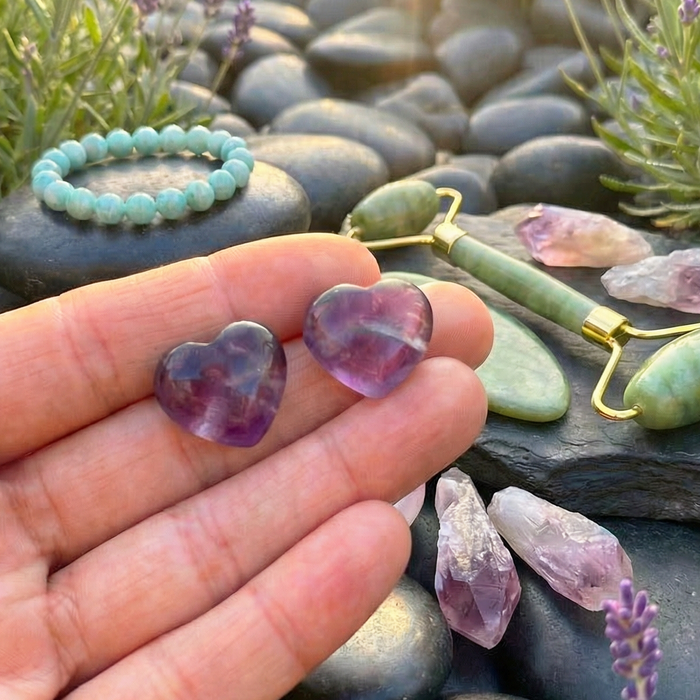Two purple fluorite hearts resting on fingertips