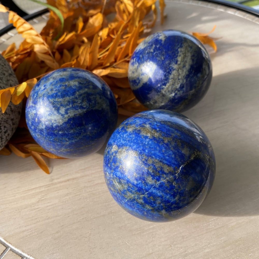 Three lapis lazuli spheres in sunlight, each with different blue, white and gold patterning