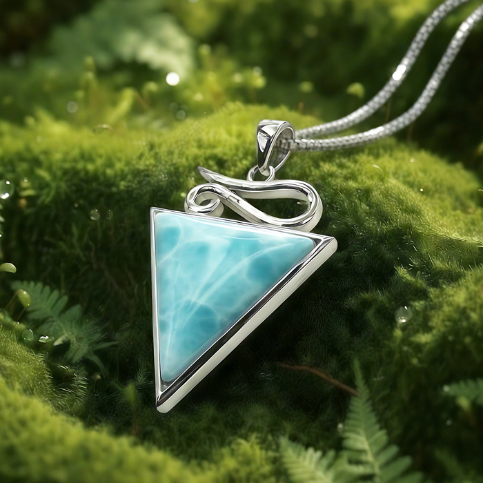Close-up of the triangular Larimar pendant in its silver frame, with a flowing silver swirl above it