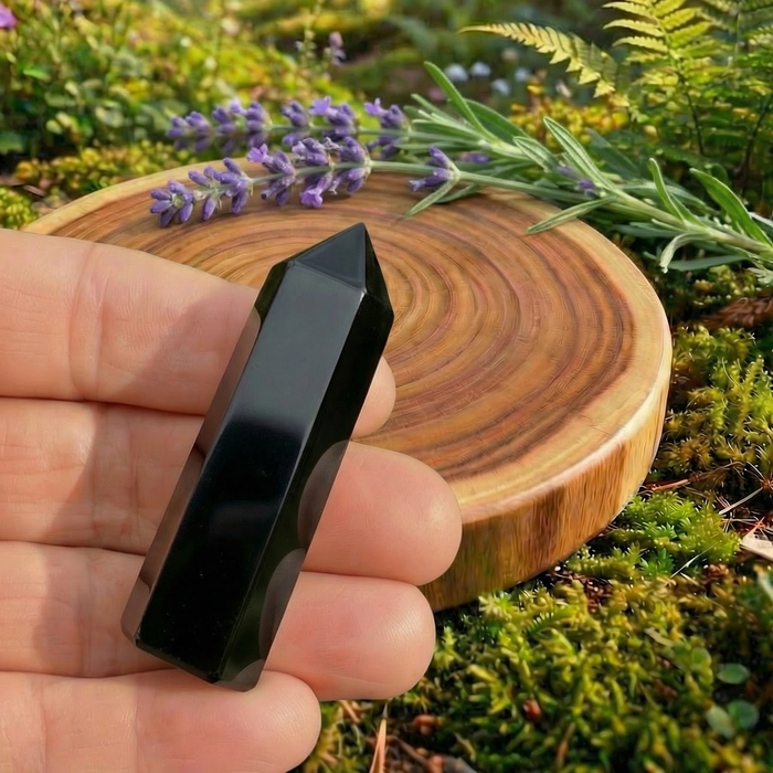 Polished black obsidian mini point held in the fingers