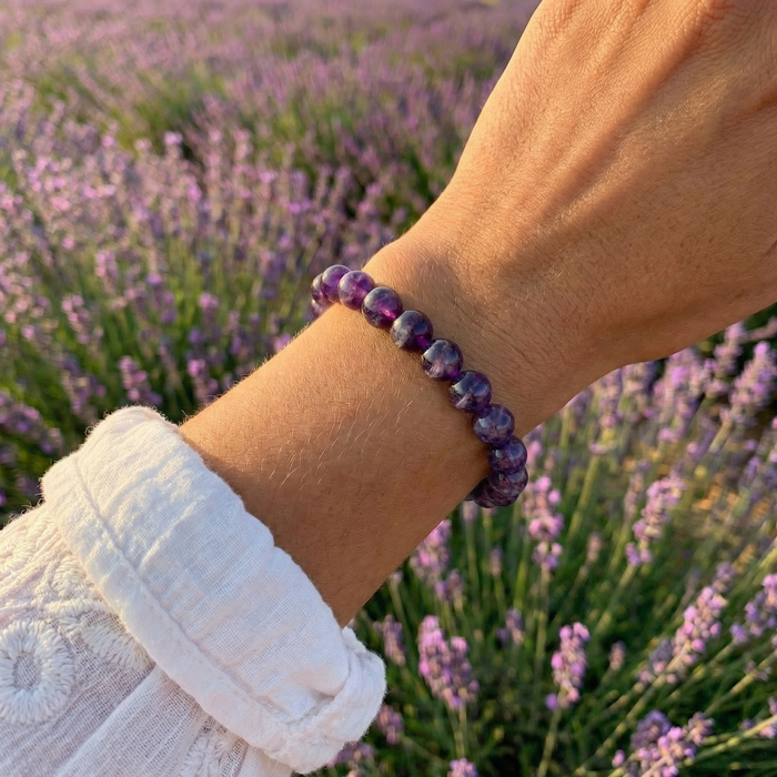 Purple amethyst bead bracelet worn on a wrist in a lavender field