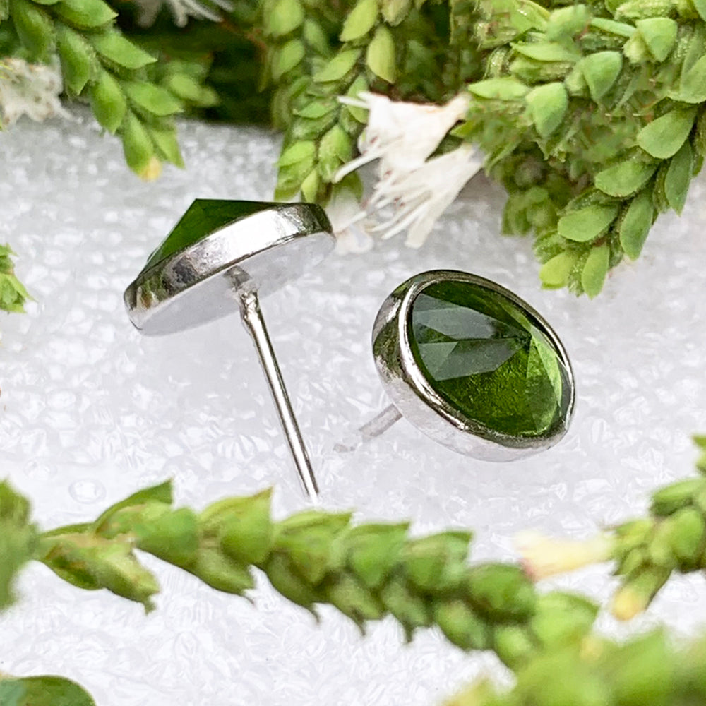 Side view of the two peridot studs showing their faceted stones, silver bezels and posts