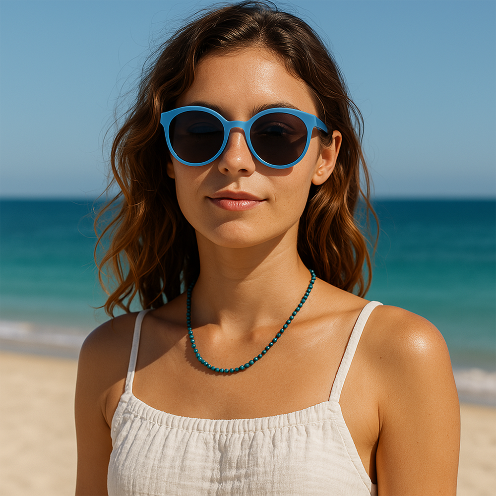 A woman on a beach wearing the green and blue phoenix lapis bead necklace at her collarbone