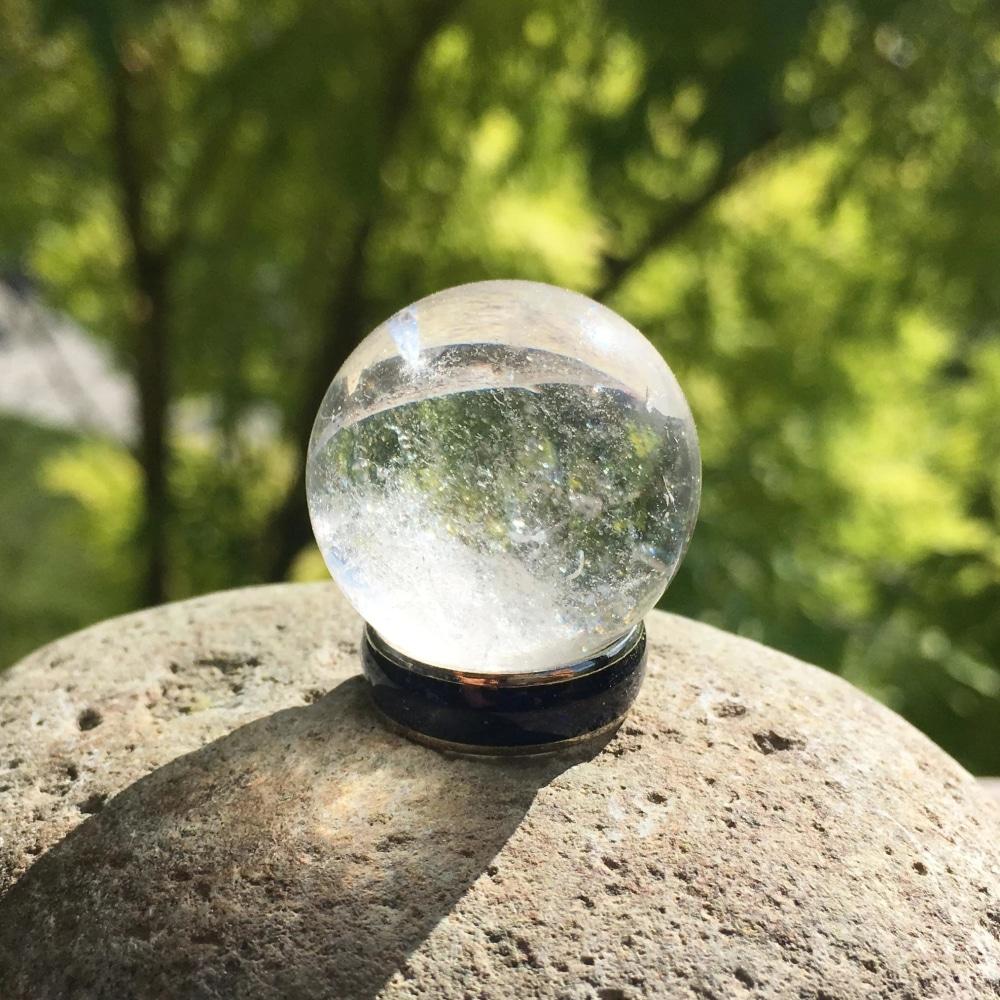 Close view of a clear quartz sphere in sunlight, clear at the top with misty white veils inside