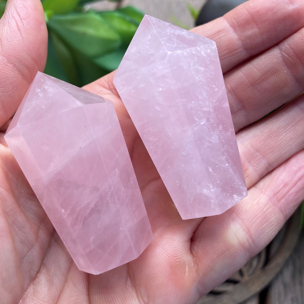 Two pink rose quartz wands resting in an open palm